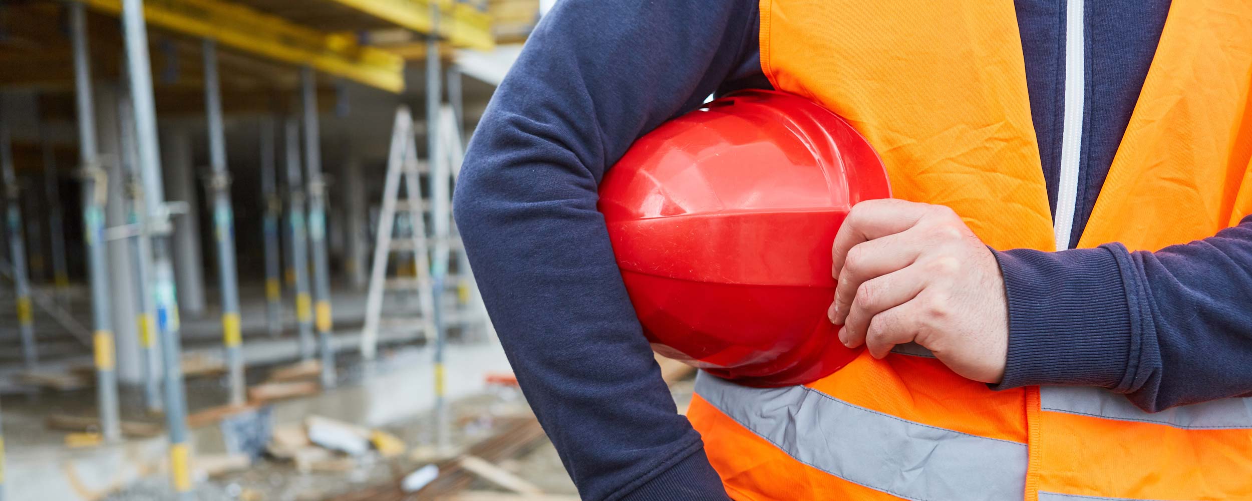 Bauarbeiter auf Baustelle mit Helm in der Hand